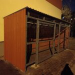 Avfallscontainerplass med trepanel og metallnett