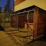 Avfallscontainerplass med trepanel og metallnett